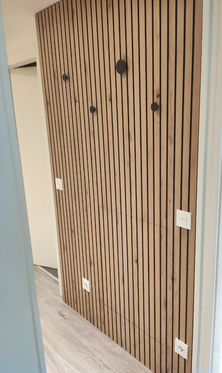 Recibidor de entrada diseñado con palilleria con unas puertas donde quedan metidas las cajas de la luz de registro y perchas