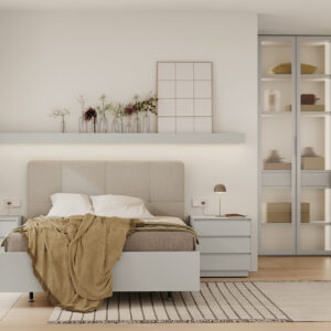 Habitación de matrimonio con cabecero tapizado en tonos grises,mesillas de tres cajones,estante con luz encima del cabecero y armario con puertas de cristal