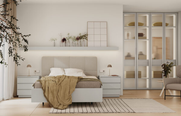 Habitación de matrimonio con cabecero tapizado en tonos grises,mesillas de tres cajones,estante con luz encima del cabecero y armario con puertas de cristal